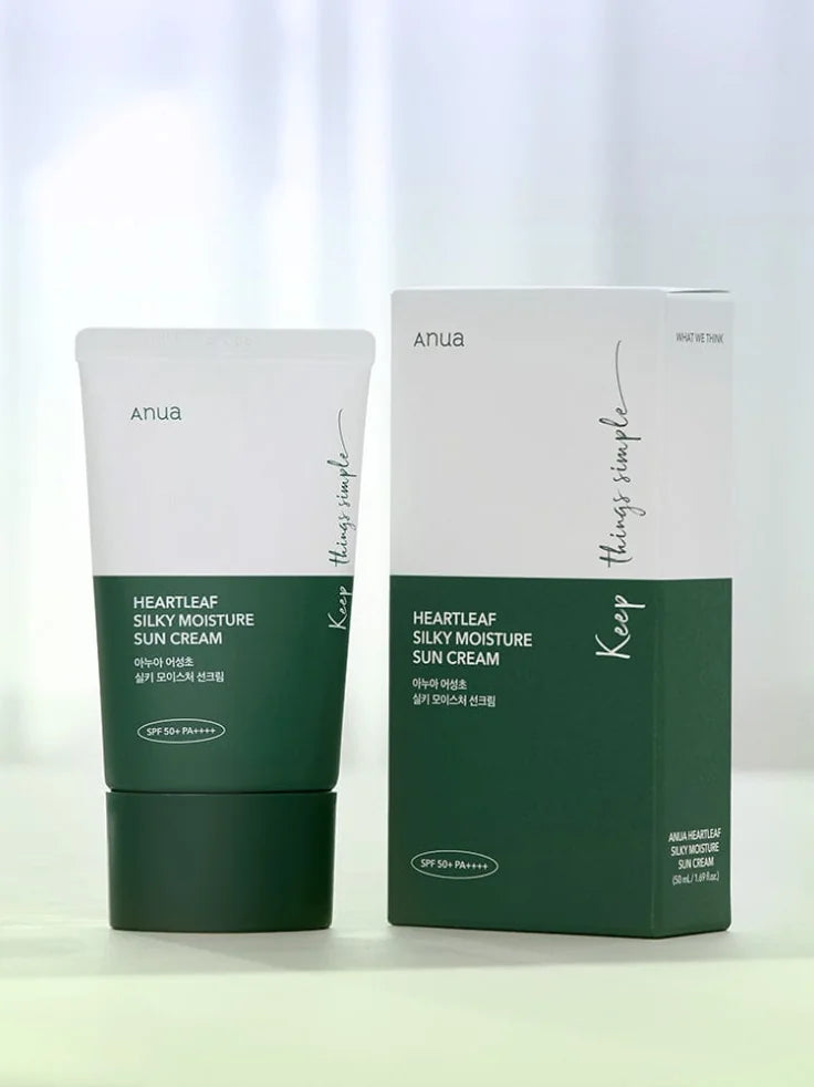 The ANUA Heartleaf Silky Moisture Sun Cream bottle next to fresh green heartleaf plants, emphasizing its key soothing ingredient.