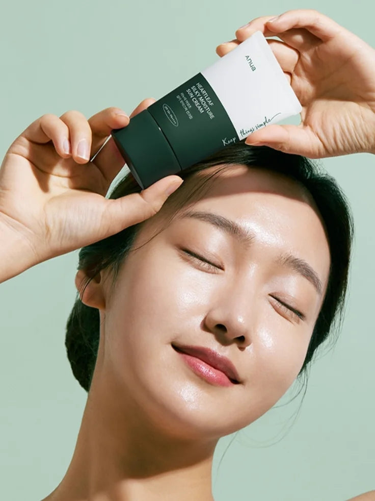 A woman applying the ANUA Heartleaf Silky Moisture Sun Cream to her face, showing its lightweight, non-greasy finish as she blends it in.