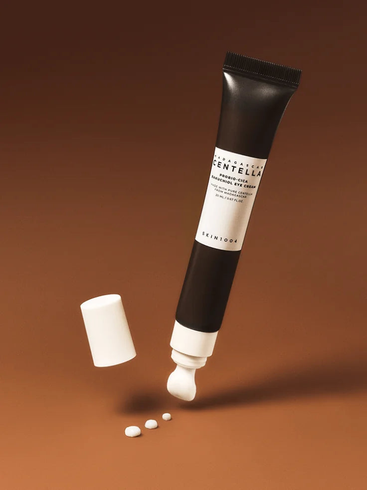 A close-up image showing the rich, creamy texture of the SKIN1004 eye cream being squeezed onto a fingertip.