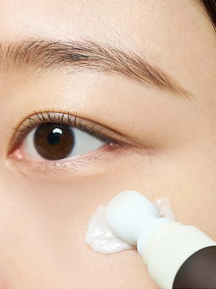 A close-up image showing the rich, creamy texture of the SKIN1004 eye cream being squeezed onto a fingertip.