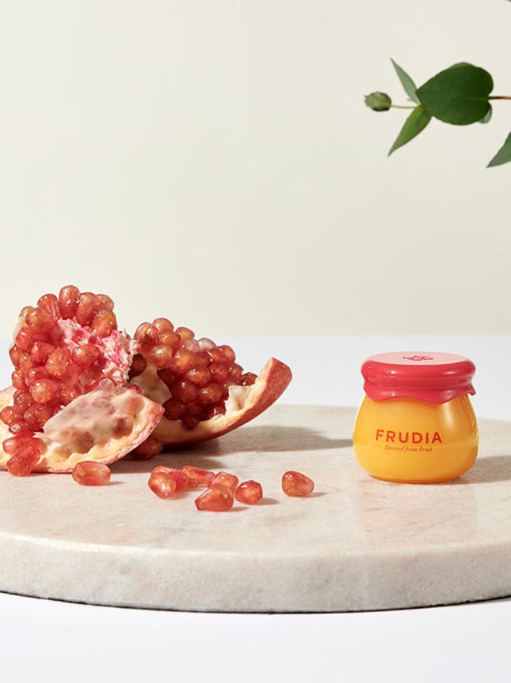 Eastern Curlew Frudia Pomegranate Honey 3 in 1 Lip Balm 10ml with Pomegranate on a stone display