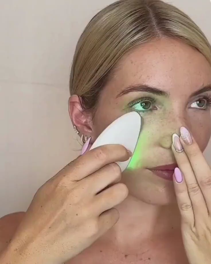 Woman using the SculptPro device with upward strokes on her jawline and neck to achieve lifting and lymphatic drainage.